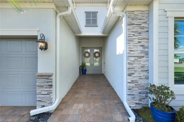 Doorway to property featuring stone siding, stucco siding, and french doors
