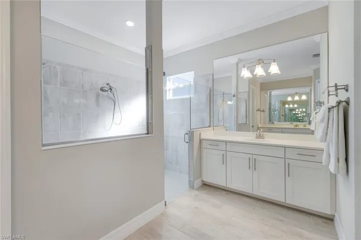 Full bath with a shower stall, vanity, and crown molding