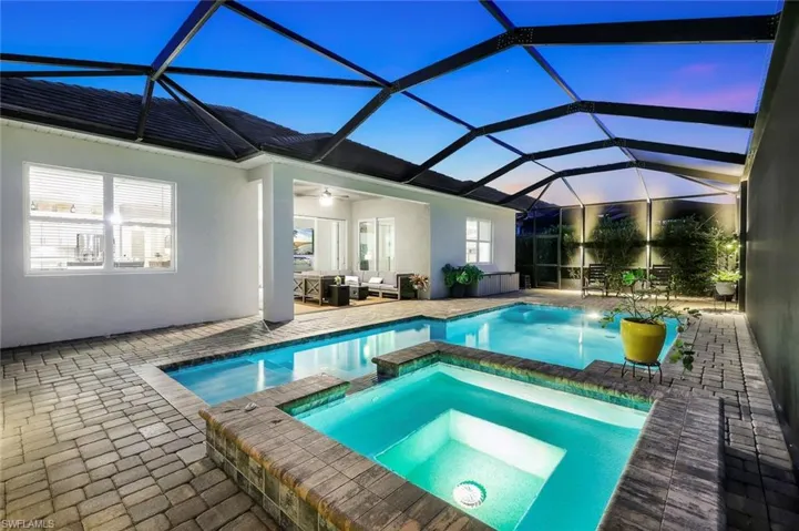 View of pool with a pool with connected hot tub, a sunroom, a lanai, an outdoor living space, and a patio