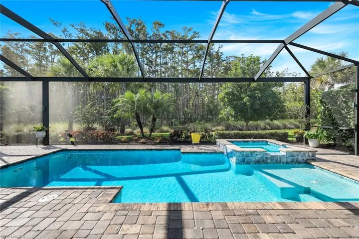View of swimming pool with a lanai, a sunroom, a pool with connected hot tub, and a patio area