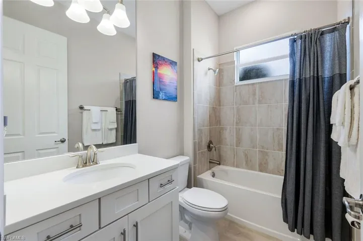 Bathroom featuring shower / bath combo with shower curtain, vanity, and a chandelier