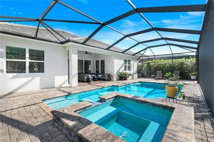 View of swimming pool featuring a sunroom, a patio, a pool with connected hot tub, glass enclosure, and ceiling fan