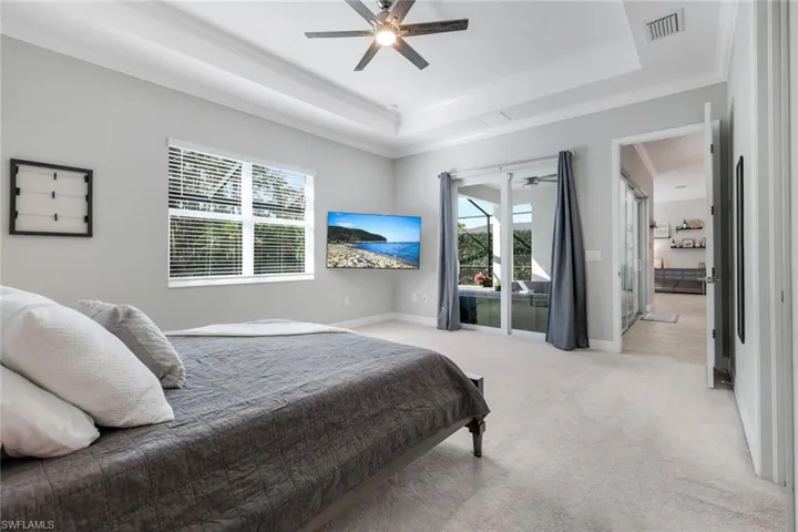 Bedroom featuring access to outside, crown molding, a tray ceiling, light carpet, and a ceiling fan