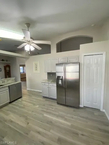 Kitchen featuring light gray cabinets, ceiling fan, decorative backsplash, appliances with stainless steel finishes, and light hardwood / wood-style floors