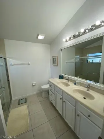Bathroom featuring a stall shower, a sink, and vaulted ceiling
