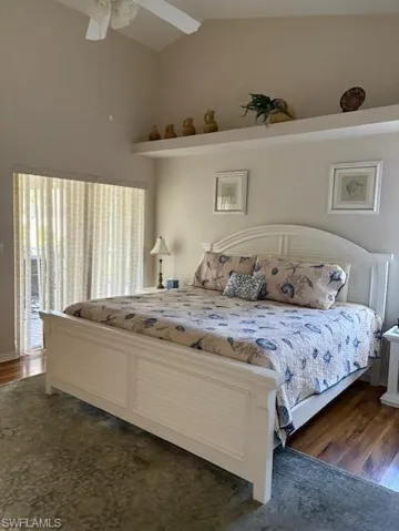 Bedroom with a ceiling fan, vaulted ceiling, and dark wood-style floors