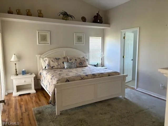 Bedroom with wood finished floors, baseboards, and lofted ceiling