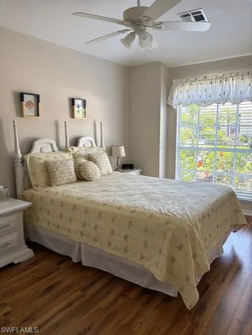 Bedroom featuring dark wood-type flooring, a ceiling fan, multiple windows, and visible vents