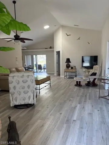 Living area featuring high vaulted ceiling, light wood finished floors, and a ceiling fan