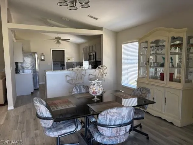Dining space featuring a ceiling fan, visible vents, wood finished floors, lofted ceiling, and baseboards