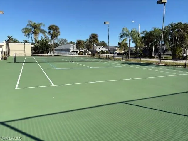 View of tennis court featuring basketball hoop