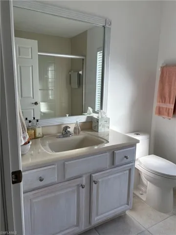 Bathroom with toilet, vanity, tile patterned floors, and walk in shower
