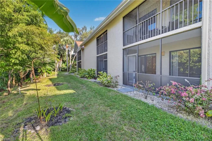 View of grassy yard with a sunroom and a balcony