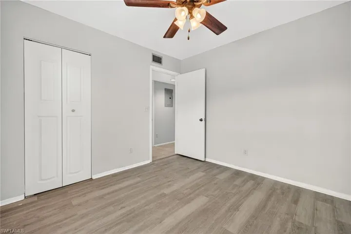 Unfurnished bedroom featuring light wood-type flooring, a ceiling fan, a closet, and electric panel