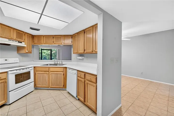 Kitchen featuring white appliances, light tile patterned flooring, and light countertops
