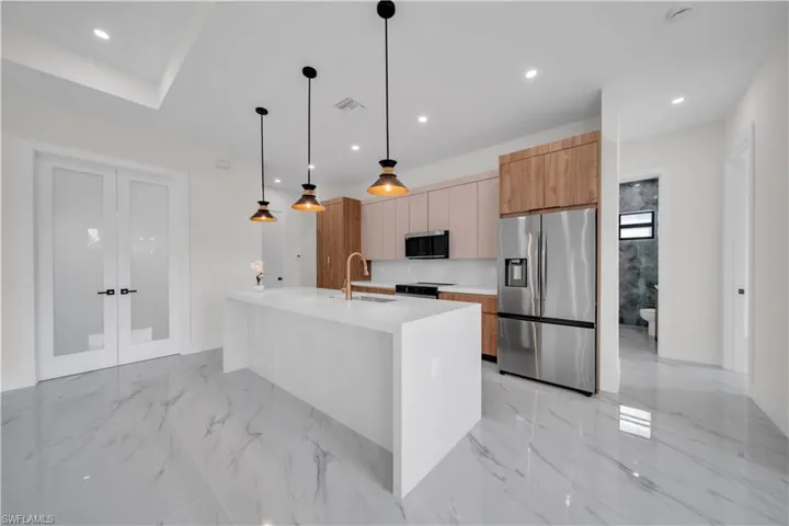Kitchen with stainless steel appliances, modern cabinets, light stone counters, light marble finish flooring, and recessed lighting
