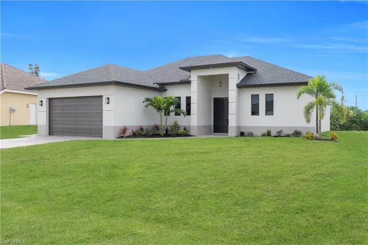 Prairie-style house with stucco siding, a front lawn, driveway, and a garage