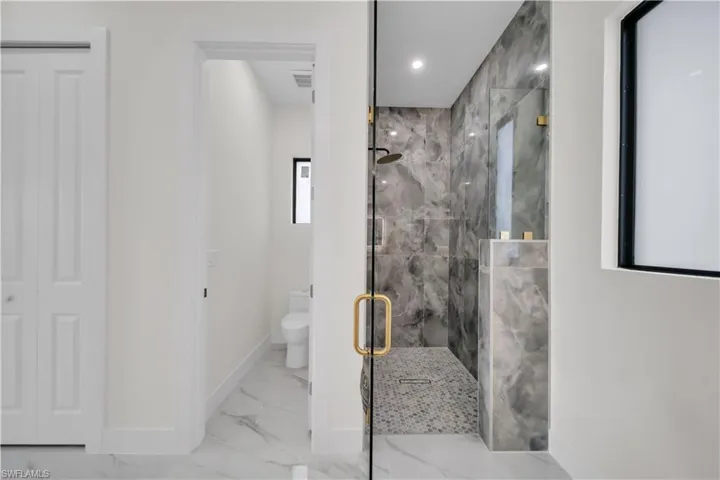 Bathroom featuring a marble finish shower and marble look tile flooring
