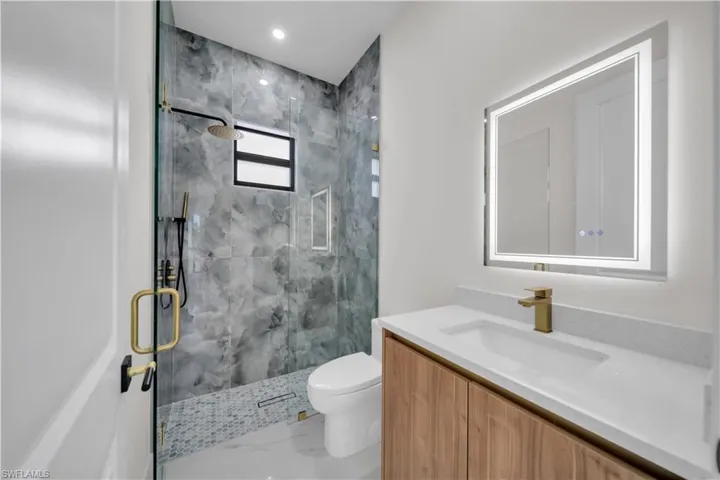 Bathroom with a marble finish shower, vanity, and light marble finish floors