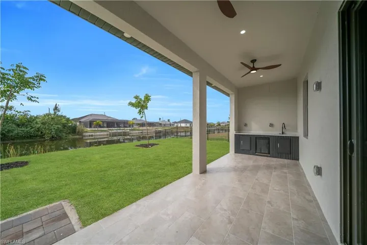 Fenced backyard featuring a patio, an outdoor kitchen, a water view, and ceiling fan