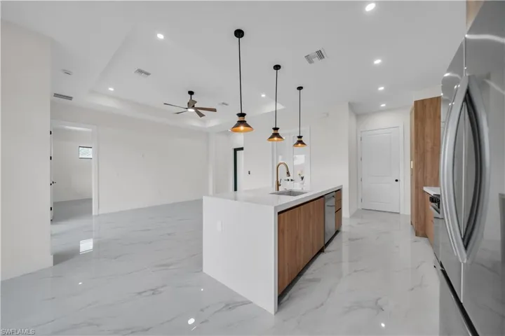 Kitchen featuring appliances with stainless steel finishes, light stone counters, decorative light fixtures, recessed lighting, and modern cabinets