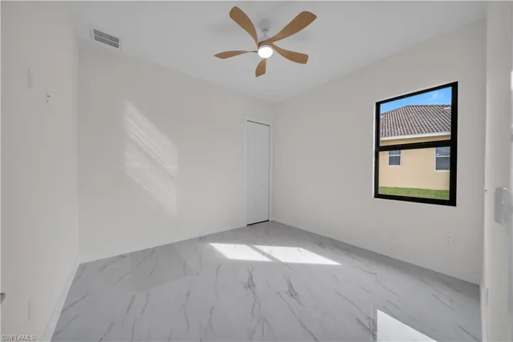 Spare room with marble look tile flooring and ceiling fan