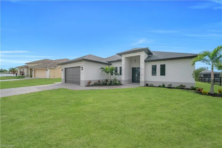 Prairie-style home with stucco siding, a front lawn, driveway, and a garage