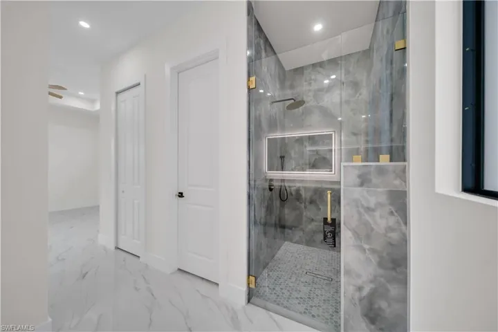 Bathroom featuring marble look tile flooring, a marble finish shower, and recessed lighting