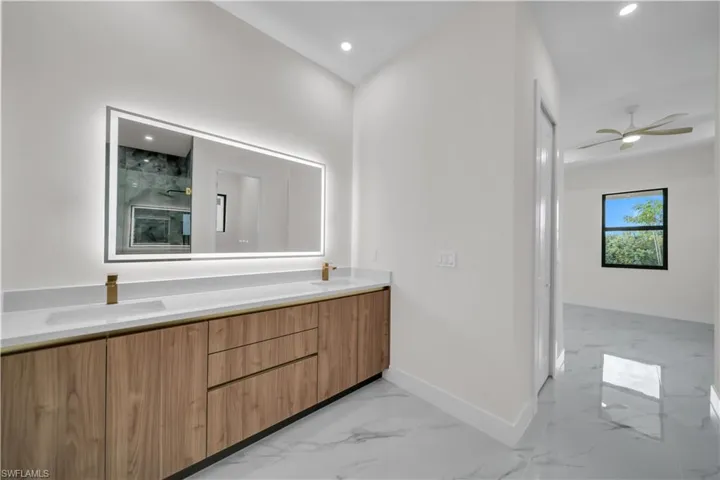 Full bathroom with light marble finish floors, double vanity, a marble finish shower, a ceiling fan, and recessed lighting