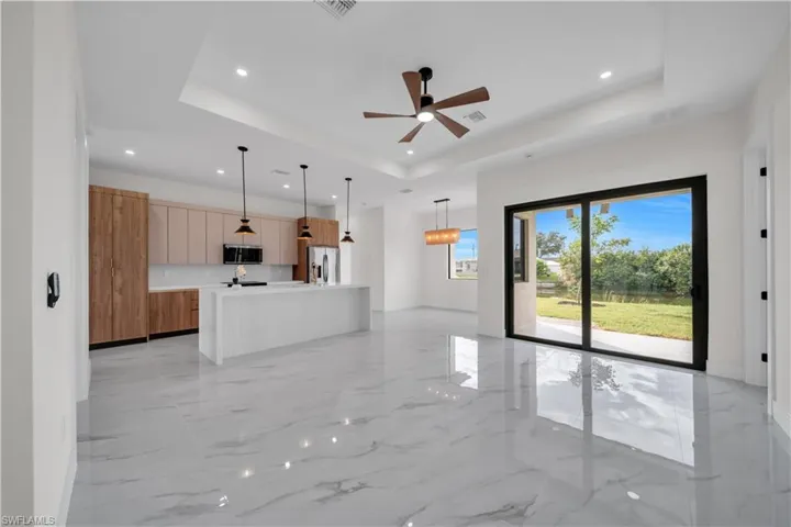 Unfurnished living room with light marble finish flooring, a raised ceiling, ceiling fan, and recessed lighting