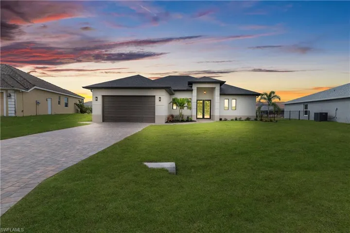 View of front of property with decorative driveway, a front lawn, a garage, roof with shingles, and stucco siding