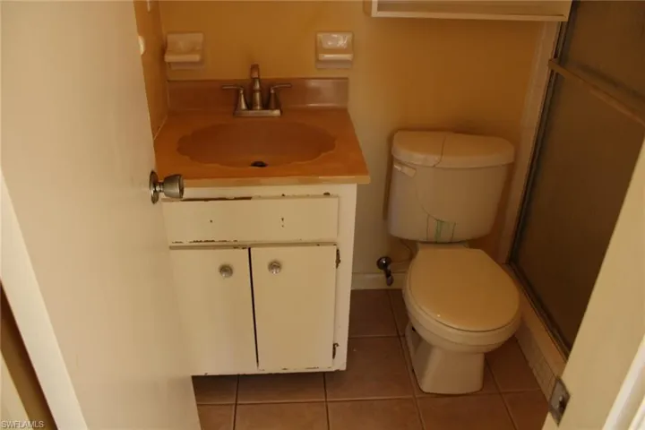 Bathroom with tile patterned flooring, vanity, a shower with shower door, and toilet