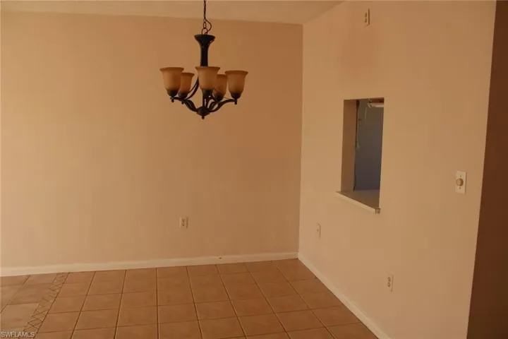 Tiled empty room featuring an inviting chandelier