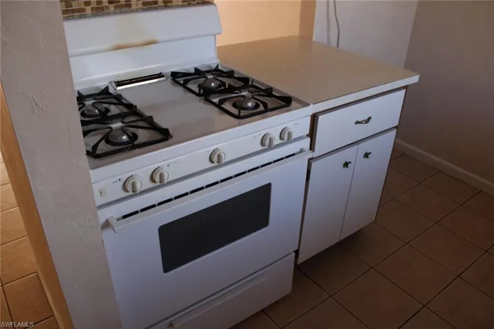Kitchen with white cabinetry, gas range gas stove, and tile patterned flooring