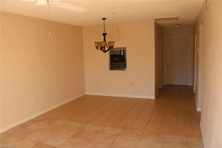 Tiled spare room featuring a notable chandelier