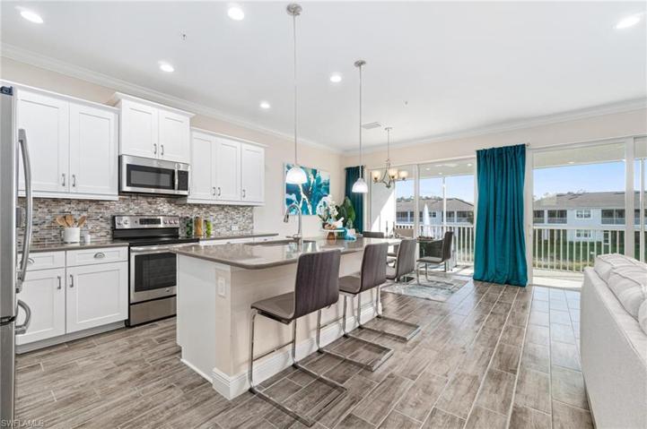 Open kitchen showcasing glass tile backsplash and center island with pendant lighting.