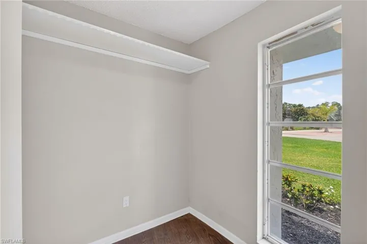 This flex room off the foyer can be an office "with a window"  featuring a single paned window, white trim, light-colored walls, wood-finish flooring, and a built-in shelf