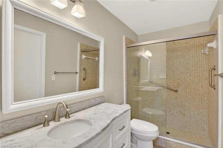 Bathroom featuring a white vanity with a marble-finish countertop, brushed nickel faucet, and an undermount sink