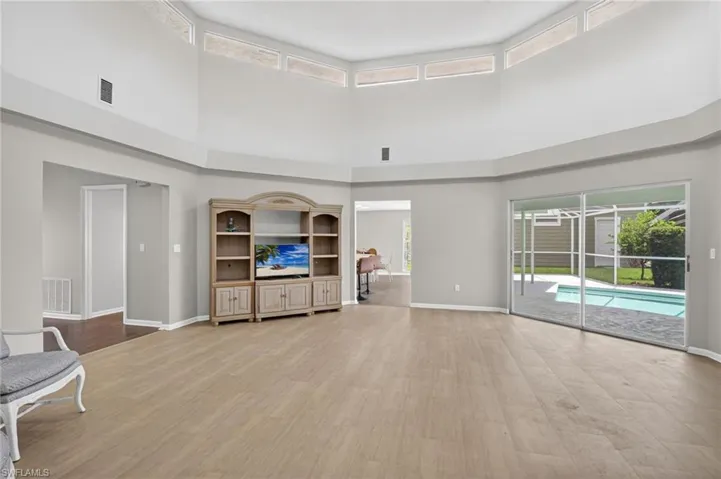 Living area featuring vaulted ceilings, light wood-finish flooring, and a neutral color palette