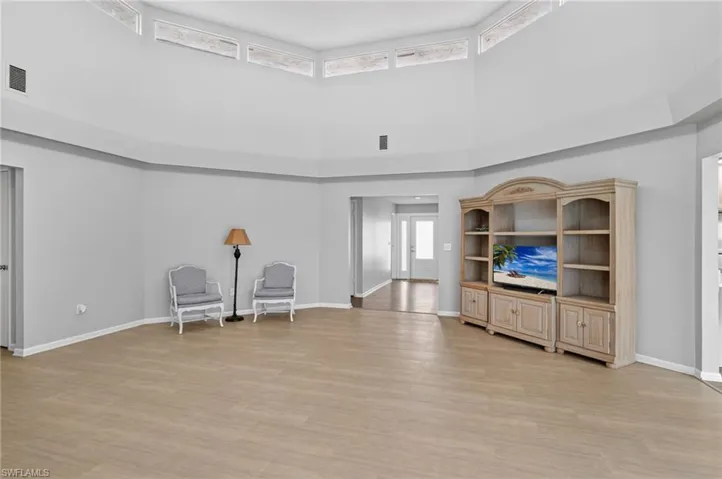 Spacious living area featuring high ceilings, wood-finish flooring, and ample natural light from upper windows