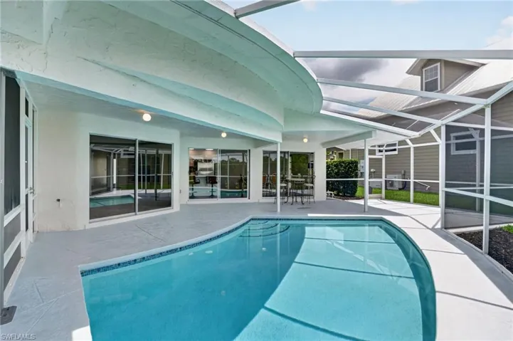 Screened-in pool deck  with shad and sun, featuring a curved swimming pool with blue tile accents