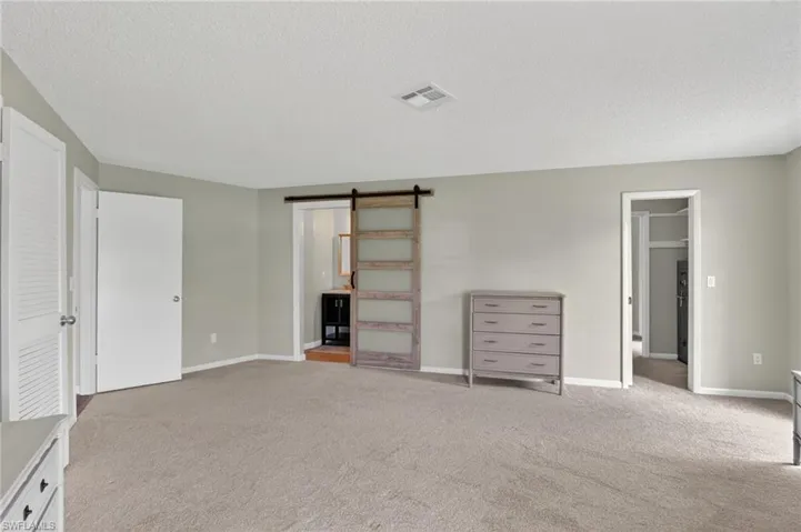 Neutral-toned carpeting and light gray walls create a cohesive aesthetic. Safe in closet for your cherished  belongings.