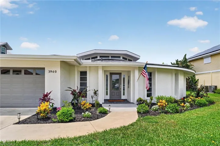 White stucco exterior with a multi-pane front entry door, a octagonal skylight feature, an attached garage, and a curved concrete walkway and refreshed landscaping