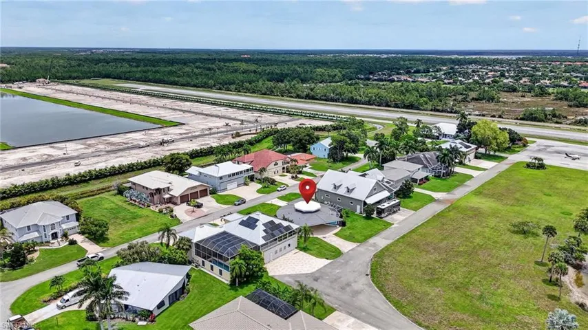 Aerial perspective showcasing a residential street with diverse architectural styles, taxiway, runway , and new single family home community adjacent but NOT connected