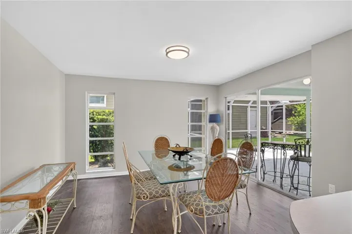 Dining area featuring wood-finish flooring, light gray walls, lanai and pool view