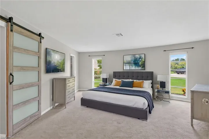 Spacious room featuring light gray carpeting and multiple windows