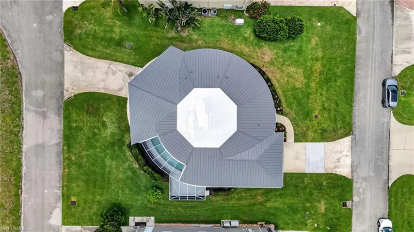 Octagonal roofline with a windows all around the raised central portion, surrounded by lush green lawns and concrete driveways