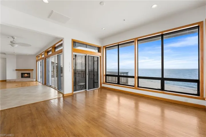 Unfurnished living room featuring wood finished floors, ceiling fan, a fireplace, a water view, and recessed lighting