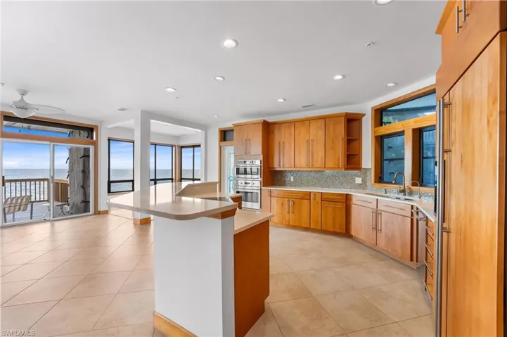 Kitchen with open shelves, backsplash, light countertops, light tile patterned floors, and a kitchen island