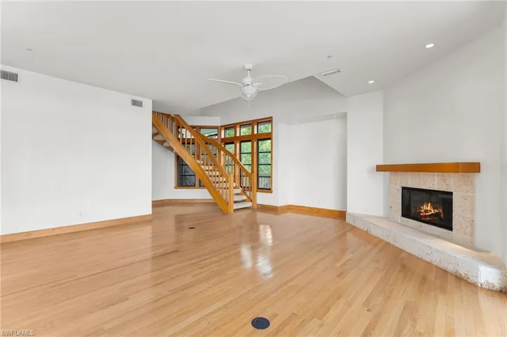 Unfurnished living room with stairway, a tiled fireplace, light wood-style floors, a ceiling fan, and recessed lighting